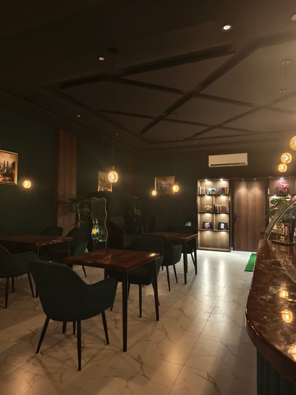 Caffio's dining room with deep green seating, polished wooden tables, and warm pendant lights